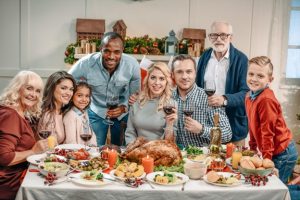 Three generations of a multi-ethnic family gathered around a holiday table in the family dining room; concept for transferring house to children in a modern family.
