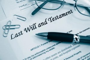 A Last Will and Testament with scattered office supplies resting on top of it.