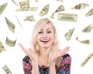 A smiling, young blonde woman surrounded by falling cash. Her inheritance money might be protected from creditors or poor financial choices with a lifetime asset protection trust.