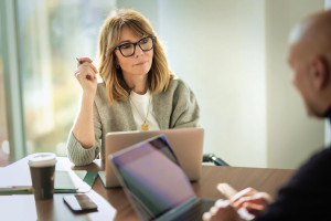 An attorney and client sit at a conference table with their laptops open, reviewing estate documents and procedures for probate administration.